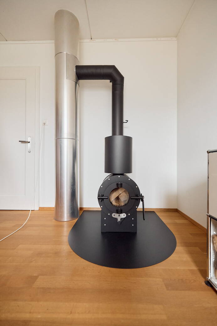 Schwedenofen Firetube Shorty slick, 360° drehbar Stahl schwarz, Grundmodul, Sockel 60 mm hoch Montagebeispiel